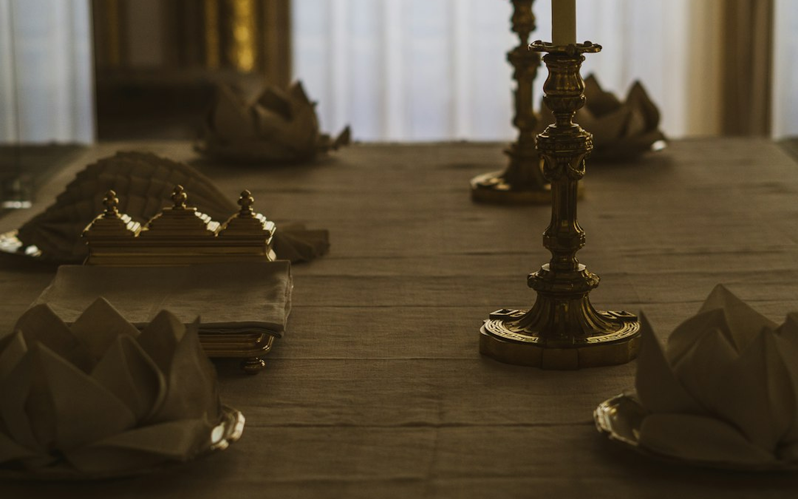 Dressed table detail with brass lanterns and a wall uplight behind