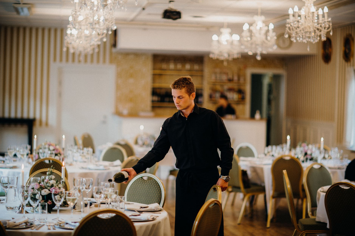 Function room set with three baize gaming tables, warm low light and adult guests in black tie
