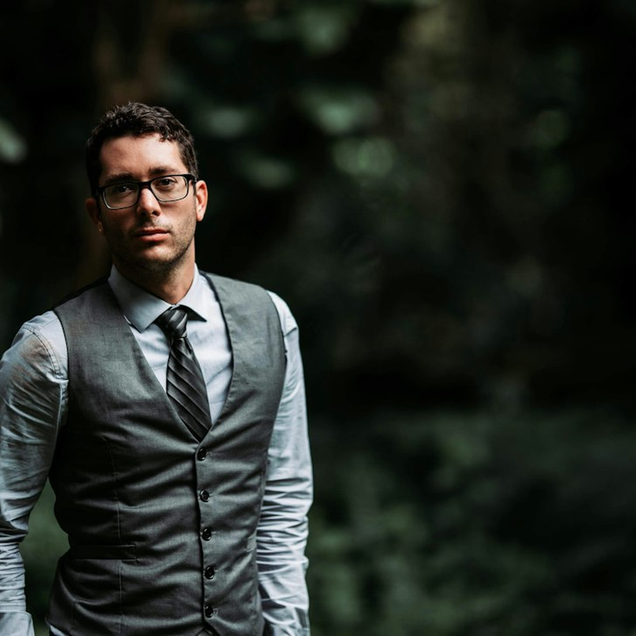 Event host in a dark waistcoat mid-explanation with one hand raised
